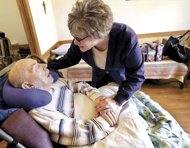 Photo courtesy: Agri-view. Angie Stone of HyLife oral care services greets George Schmidt, 88, before caring for his teeth at Huntington Place in Janesville.