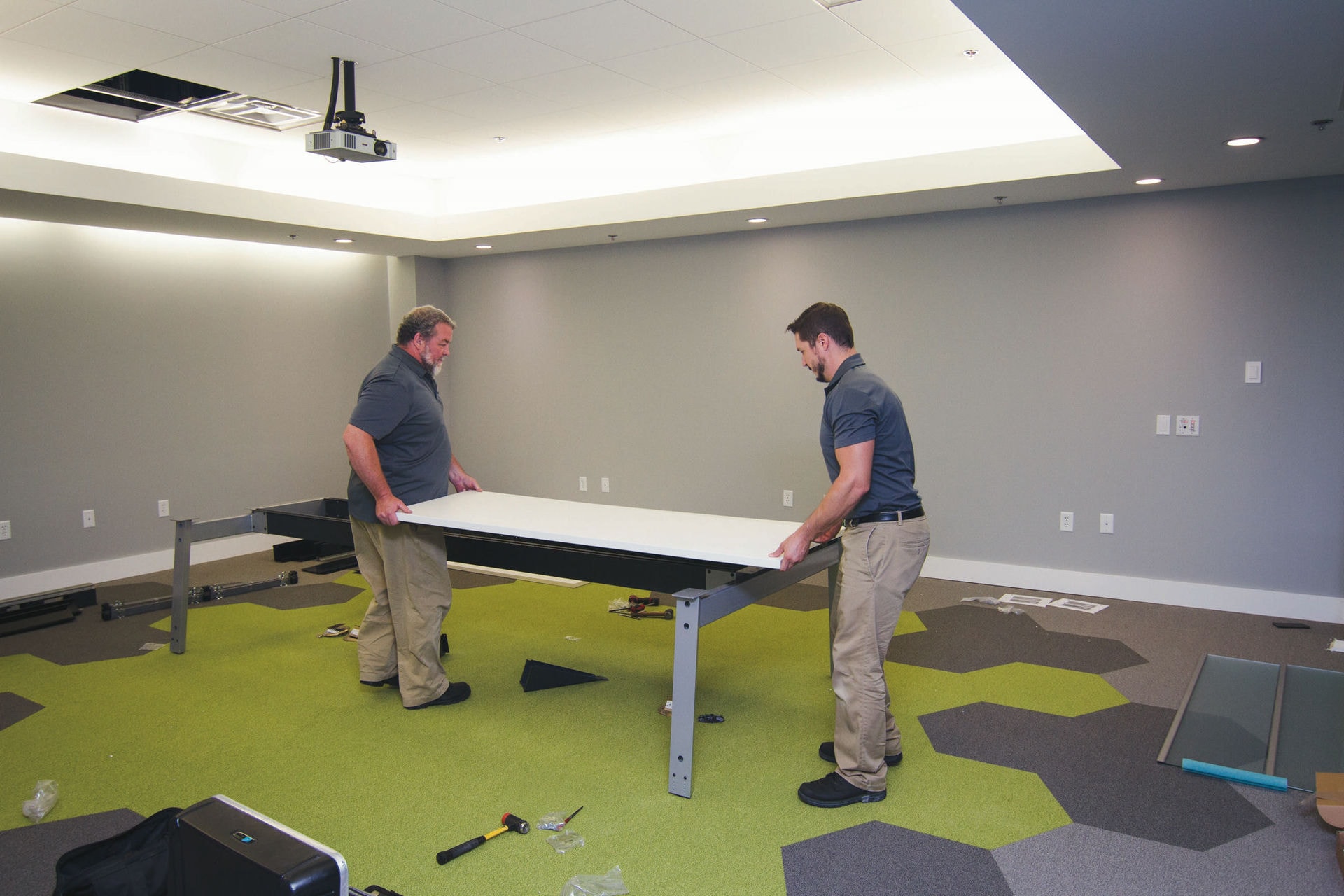 Two members of Benco staff assemble a table.