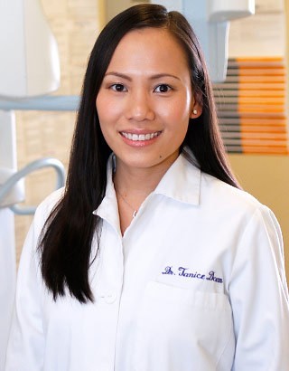 Dr. Janice Doan faces the camera smiling wearing a white buttoned shirt.