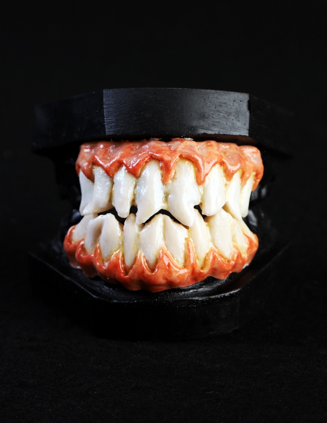Close-up image of a model of sharp monster teeth and red gums.