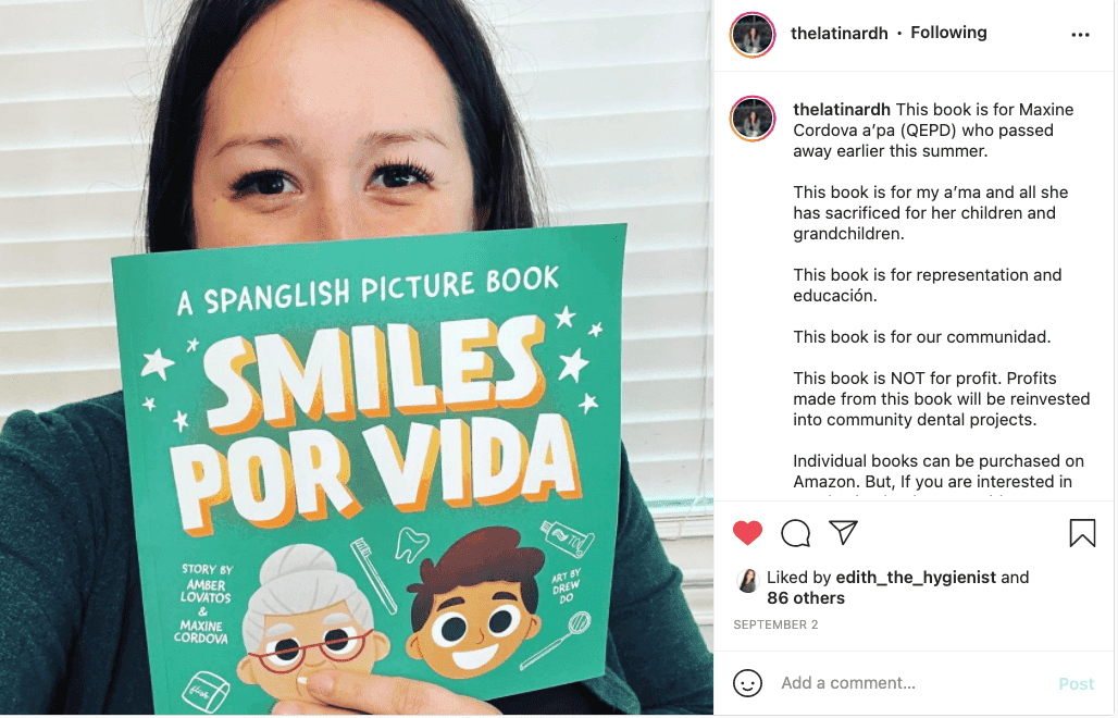 Amber Lovatos, BSDH, RDH holding her children’s book about oral health, “Smiles Por Vida" in front of her face.