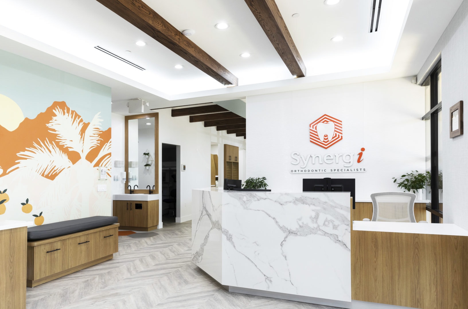 Interior view of Synergi Orthodontic Specialists including a reception desk on the right and a mural depicting citrus groves on the left.