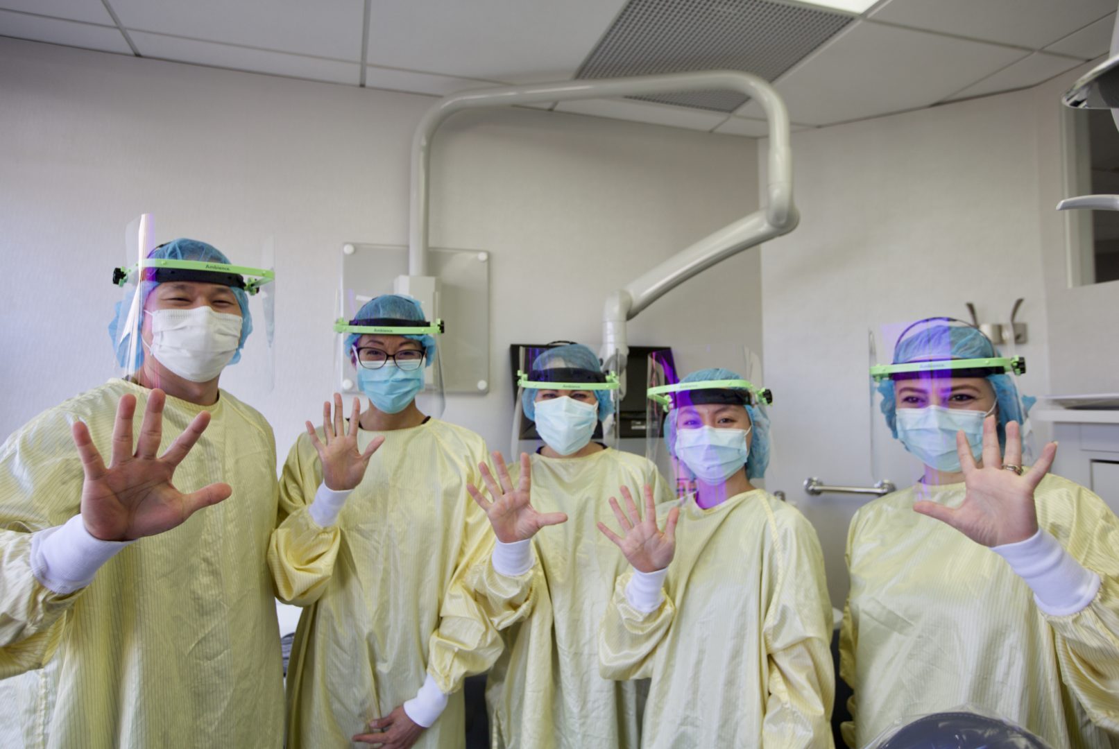 Dr. Michelle Lee and Dr. Andrew Han with their team, shown, wearing the Ambience Shield which was created but a father --son duo to improve clarity and dental loupe fit while protecting against splatter.
